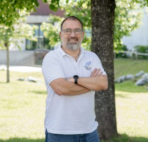 Ein Mann steht auf einer Wiese und schaut in die Kamera